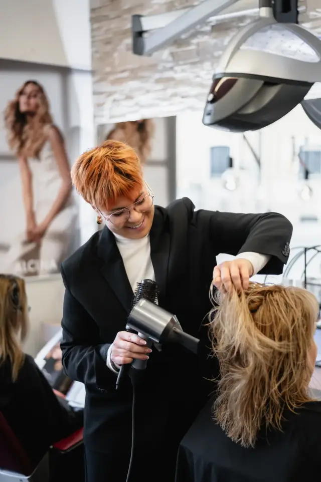 Stylistin föhnt blondes Haar am Stylingplatz bei Kaiserreich Hairstyle in Nürnberg