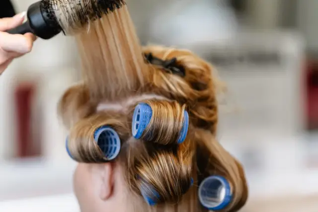 Blaue Wickler im blonden Haar einer Kundin bei Kaiserreich Hairstyle in Nürnberg