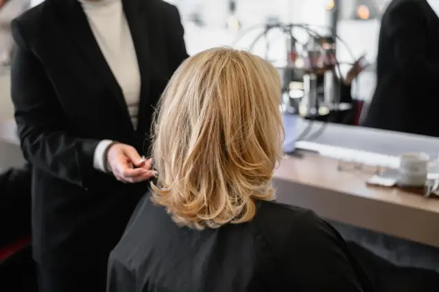 Stylistin formt einen blonden Bob mit den Händen bei Kaiserreich Hairstyle in Nürnberg