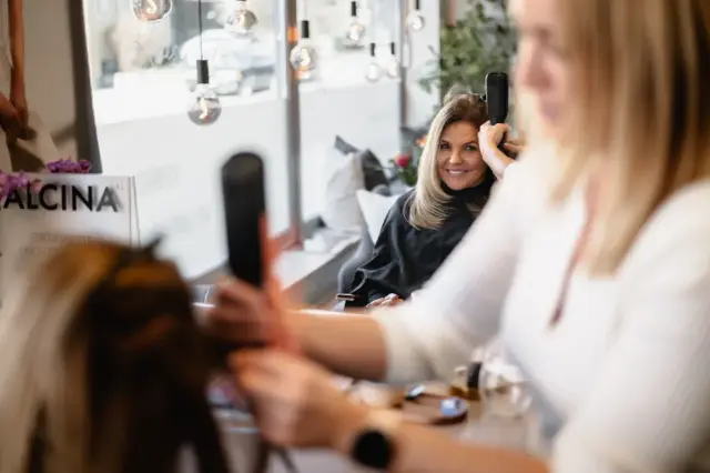 Kundin lächelt während des Stylings in den Spiegel bei Kaiserreich Hairstyle in Nürnberg