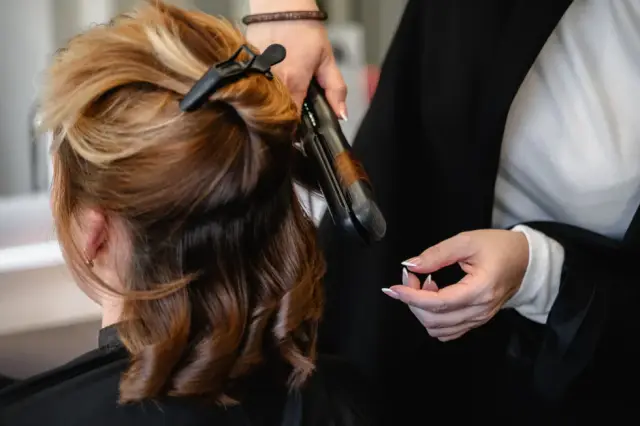 Lockenstab formt braunes Haar in Nahaufnahme bei Kaiserreich Hairstyle in Nürnberg