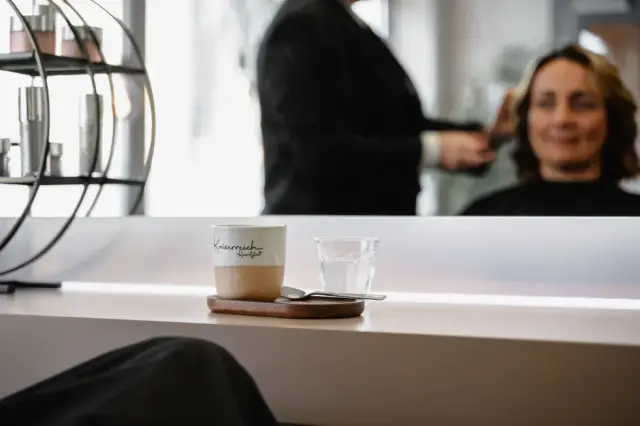Kaffeetasse und Wasserglas auf einer Ablage vor dem Spiegel bei Kaiserreich Hairstyle in Nürnberg