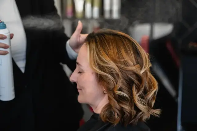 Brünette Kundin im Profil mit gestylten Locken bei Kaiserreich Hairstyle in Nürnberg