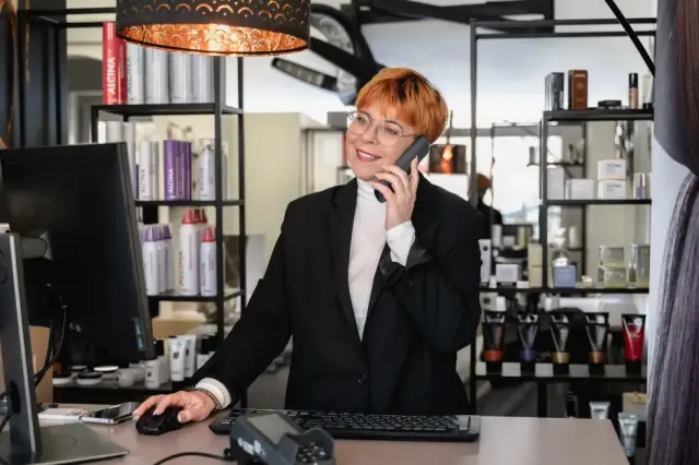 Stylistin sitzt telefonierend an der Rezeption bei Kaiserreich Hairstyle in Nürnberg