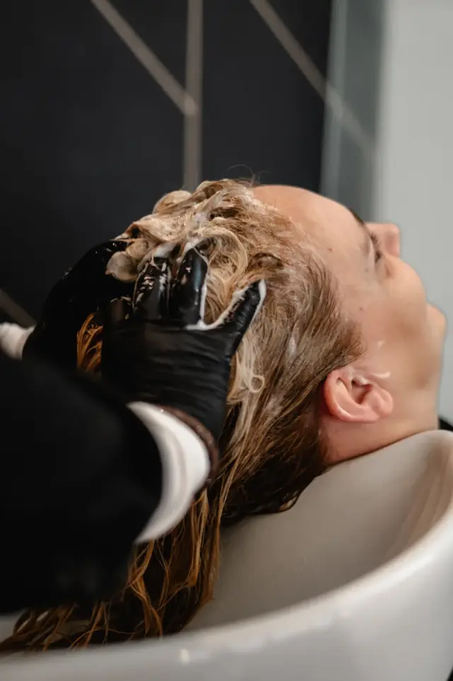 Kundin mit Pflege- oder Farbprodukt im Haar am Waschbecken bei Kaiserreich Hairstyle in Nürnberg